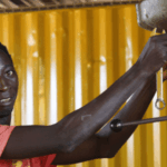 Welding graduate Augusto from Guinea-Bissau adjusts a drill press in a workshop.